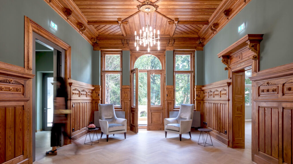 Elegantes Foyer in traditioneller Holzarchitektur mit modernen Sitzmöbeln und Beleuchtung